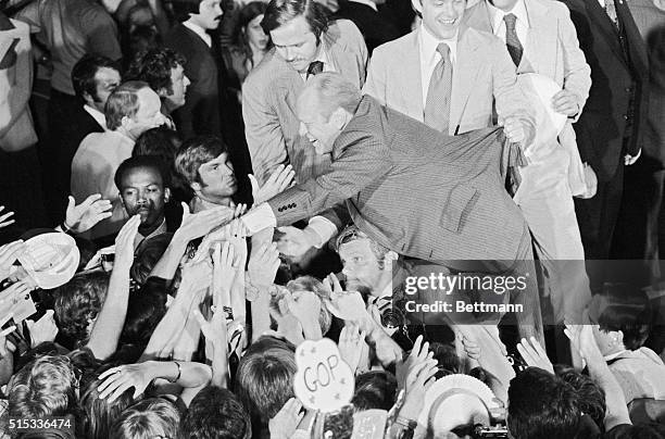 Reaching out to his cheering supporters, President Ford is prevented from falling into the crowd by son Jack. Crowd turned out to greet Ford upon his...