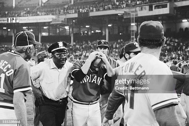 Cleveland Indians relief pitcher Tom Hilgendorf, holding his head after being struck by a flying object, is helped off the field following a...