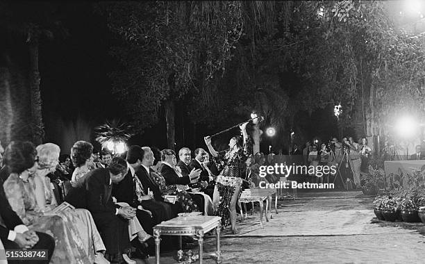 Secretary of State Henry Kissinger seems to be explaining the finer points of "belly dancing" to President Nixon as dancer Souhair Zaki puts on her...