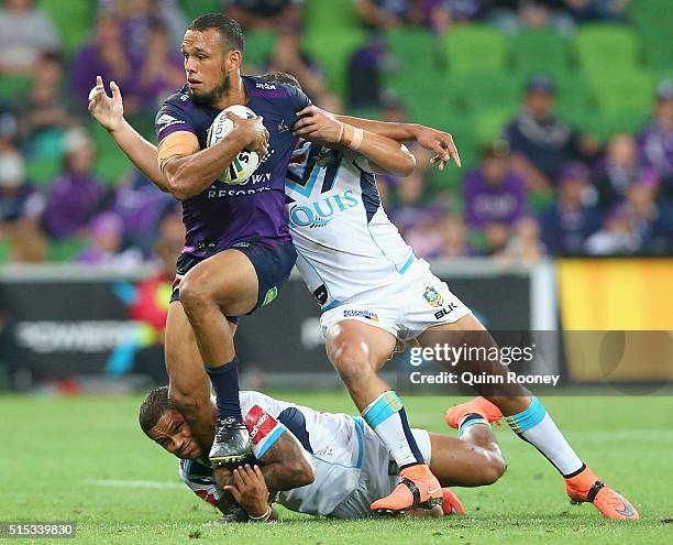 Will Chambers of the Storm breaks through a tackle by Josh Hoffman and Ashley Taylor of the Titans during the round two NRL match between the...