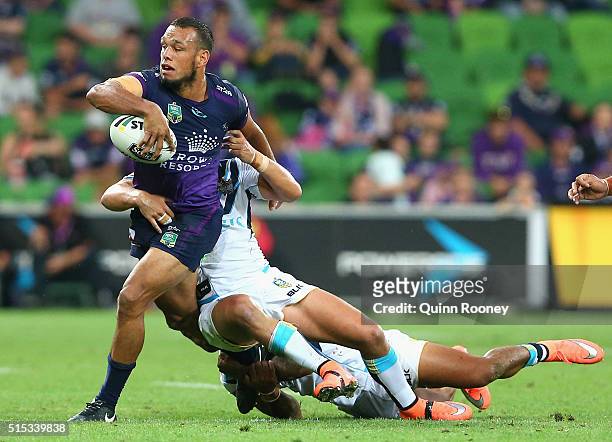 Will Chambers of the Storm breaks through a tackle by Josh Hoffman and Ashley Taylor of the Titans during the round two NRL match between the...