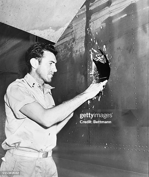 Lt. Louis Zamperini, a former University of Southern California track star, now an Army Bombardier, examines a hole in his plane after he returns...