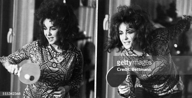 Out to win, Elizabeth Taylor takes on husband, played by Michael Caine, in a game of table tennis. The scene is from Miss Taylor's new movie, "Zee...