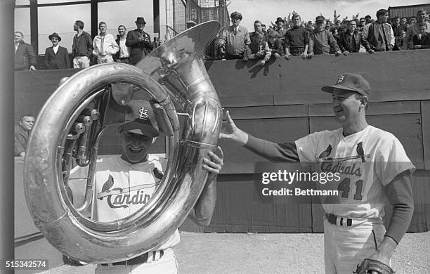 Cardinal players find time to relax in outfield and Bob Uecker even tries his hand at tuba with Roger Craig watching. Cards got into mood with 9-5...