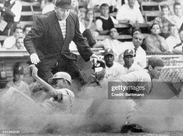 In a cloud of dust, Cubs Billy Williams slides safely across home plate as Phillies catcher Bob Uecker grabs late throw in 3rd inning of game here...