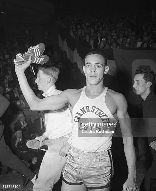 Mal Whitfield holds aloft the shoes with which he ‘burned up' the track during the Knights of Columbus meet at Madison Square Garden, Feb. 28. He...