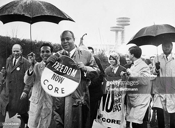 James Farmer, national director of the Congress of Racial Equality, holds a large sign as he leads a CORE demonstration during opening day ceremonies...