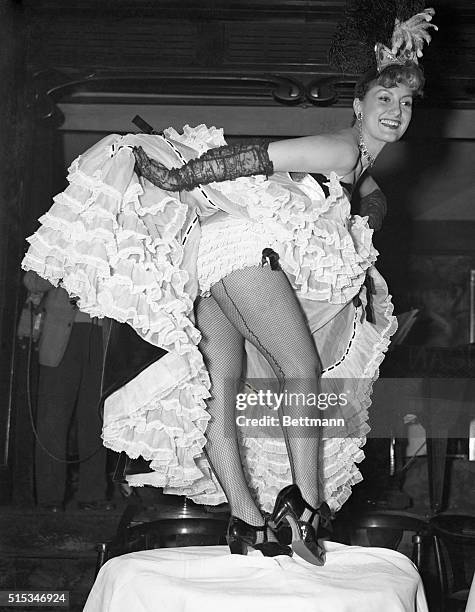 Striking a traditional "Can Can" pose, vivacious dancer, Gaby Bruyere flounces her laced skirts during a table top performance at Maxim's famed...