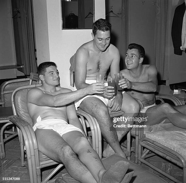 The very picture of relaxation, halfback Phil King , star place kicker Pat Summerall and quarterback don Heinrich, of the New York Giants, toast each...