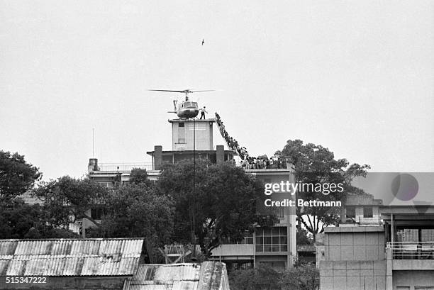 Employee helps Vietnamese evacuees onto an Air America helicopter from the top of 22 Gia Long Street, a half mile from the U.S. Embassy.