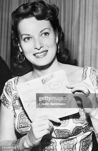 Actress Maureen O'Hara displays her passport to newsmen to support her contention that she was not even in the United States at the time she is...