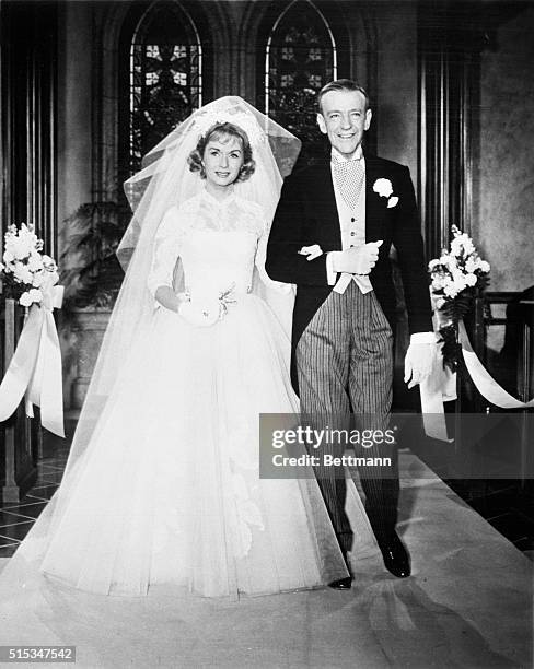 Debbie Reynolds, wearing a $4,000 wedding dress designed by Academy Award-winning stylist, Edith Head, walks down the bridal church-path with her...