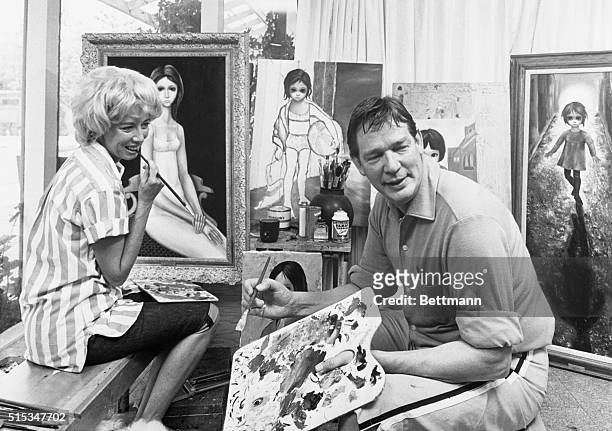 Painters Walter and Margaret Keane get busy with their palettes in the ‘Paint Room' of their home here. In background are some of the paintings of...