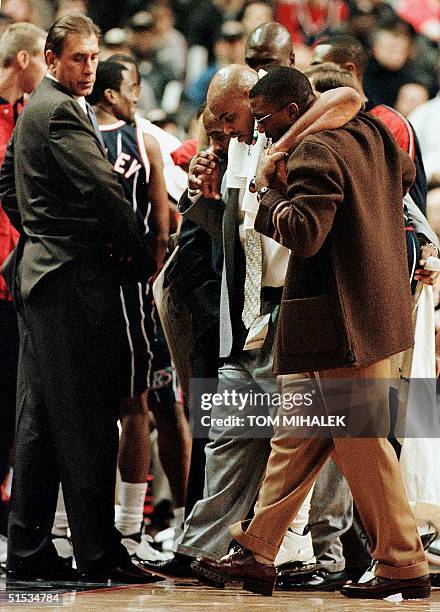 The Houston Rockets' Charles Barkley is helped off the court after injuring his left knee as head coach Rudy Tomjanovich looks on eight minutes into...