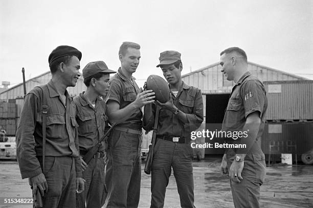 Ensign Roger Staubach, Navy's All America Quarterback and Heisman Trophy Winner, shows South Vietnamese guards how to hold a football at a naval...