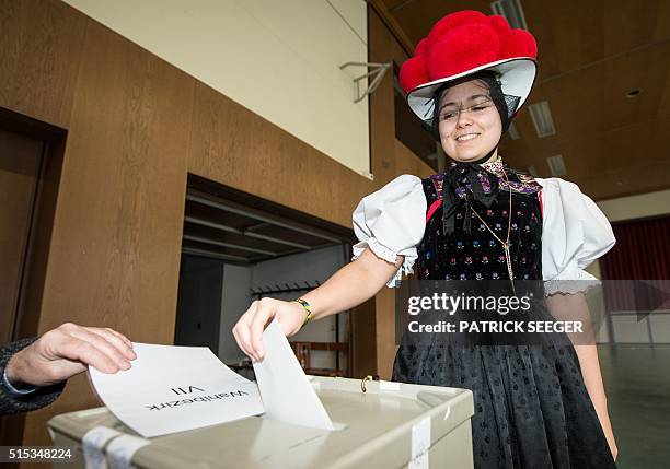 Woman wearing a traditional "Bollenhut" costume casts her ballot in Kirnbach, southern Germany during regional state elections in Baden-Wuerttemberg,...