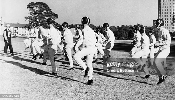 Coach Paul Bryant, extreme left, puts his University of Alabama football squad through limbering-up exercises on Rice University campus late 12/15...