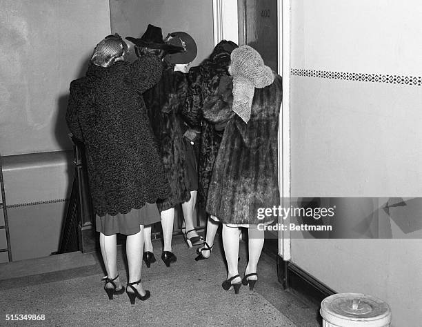 Refusing to show their faces to the camera, these girls wait to appear before U.S. Commissioner Needham C. Trunage, in Washington. They were part of...