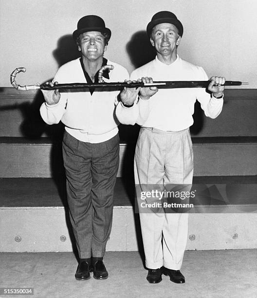 Couple of song and dance men, Burt Lancaster and Kirk Douglas polish up their routine in London for a special benefit show. Sporting British bowlers...