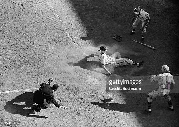 Sliding in on all fours and the seat of his pants, Ray Sanders, Card's first baseman, hits the dust on the home plate to score a run in the fourth...