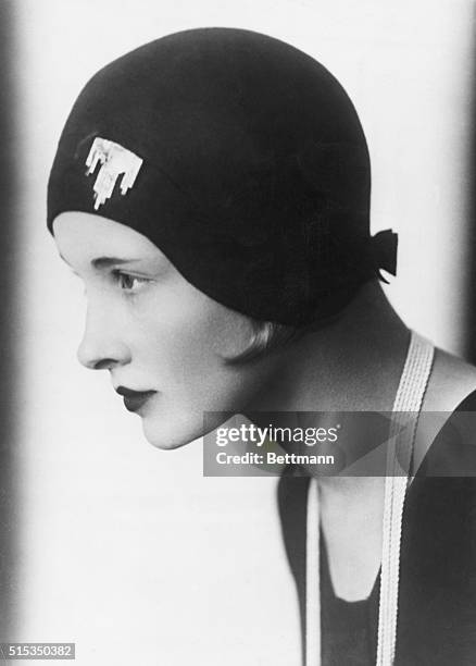 Woman modeling a hat fitted with a brooch on the front and a bow on the nape of the neck. Ca. 1925-1932.