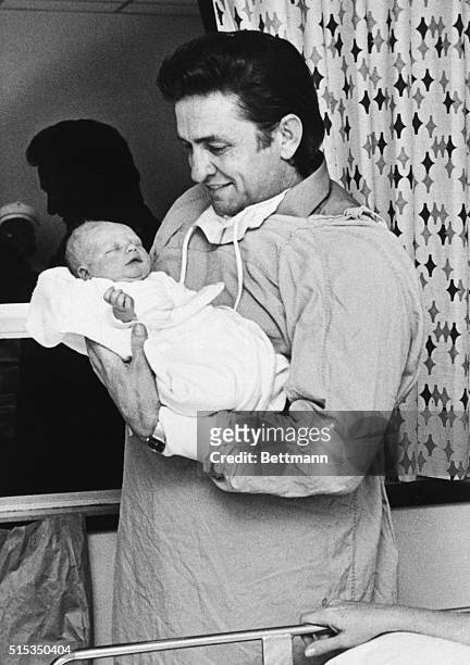 Country music singer Johnny Cash is shown holding his newborn son, John.