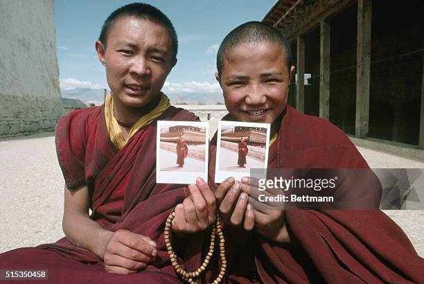 Lhasa, Tibet-: Two Buddhist monks hold up Polaroid photos of themselves. The monks were amazed by the instant photos since they are mostly cut off...