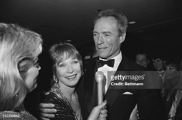 Hollywood, California- Actor Clint Eastwood walks up behind actress Shirley MacLaine and gives her a hug as she is interviewed shortly before The...