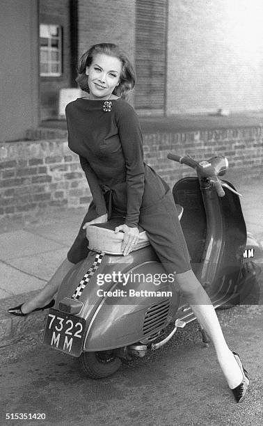 Actress Honor Blackman poses on a moped in a slender cocktail dress on the set of The Avengers television program in London. Blackman plays the role...