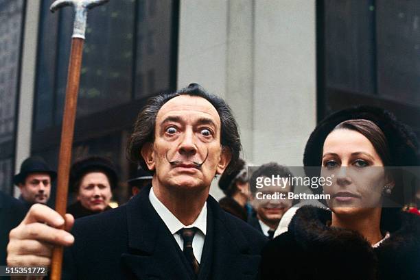 Artist Salvador Dali, lifting his cane, with a woman in New York.