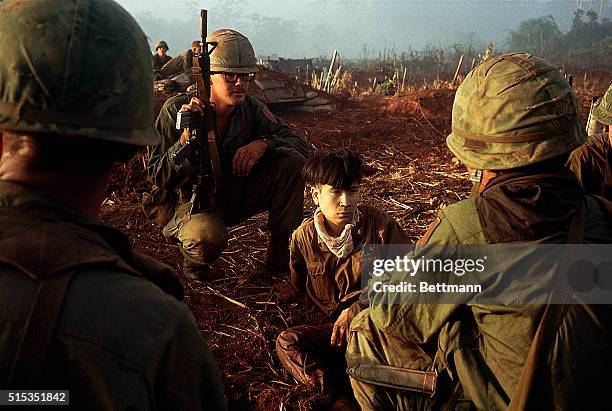 Members of the 1st Infantry Division watch over a young Vietcong prisoner of war captured during Operation Quicksilver. | Location: Near Bu Dop,...