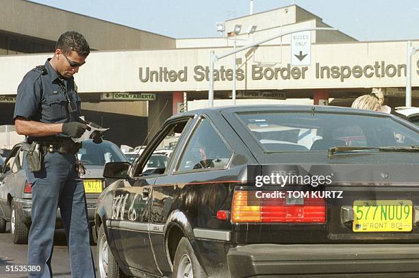 Customs inspector Jesse Austin checks immigration papers of a Mexican citizen 29 December 1999 as he waits in line to enter the United States from...