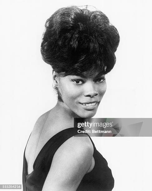 Portrait of singer Dionne Warwick wearing a black cocktail dress.