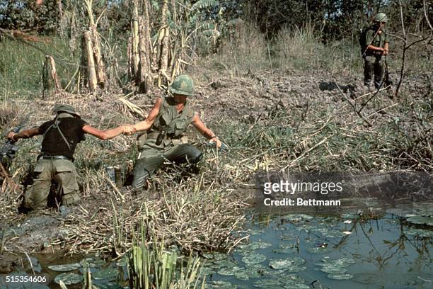 Saigon, Vietnam- Picture shows GI's of the Third Brigade of the 9th Infantry Division. They are pulling each other through a swamp near the Cambodian...