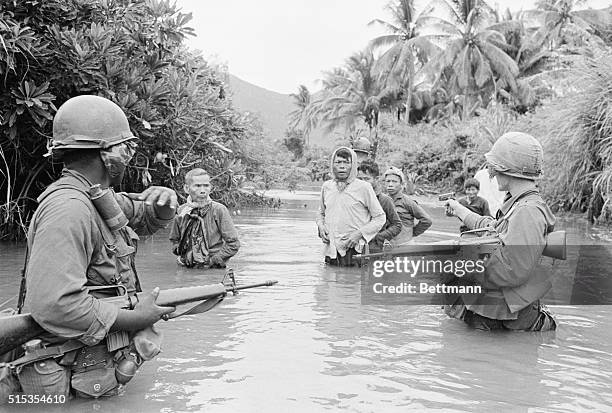 Bong Son, South Vietnam- U.S. First Cavalry troops move Viet Cong suspects across a stream just south of here, 10/19. The suspects were rounded up...