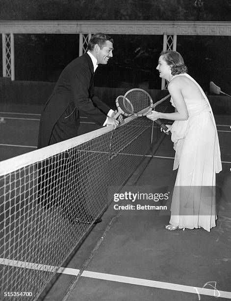 Hollywood, CA- An informal picture of Clark Gable and Carole Lombard playing tennis in formal evening attire in Hollywood recently. Today the screen...
