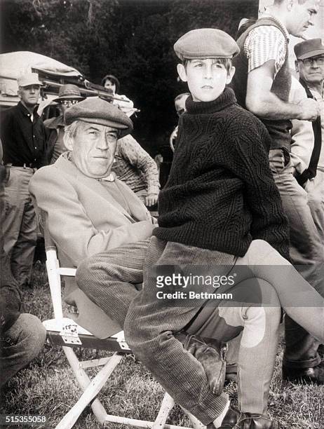Hollywood, CA- Solemn-faced Tony Huston, 13-year-old son of director John Huston, rests on his distinguished father's lap during a brief lull in the...