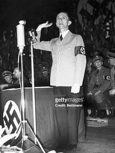 Joseph Goebbels , Nazi Propaganda Minister, is shown standing at what appears to be a rally, hand raised. Undated photograph.