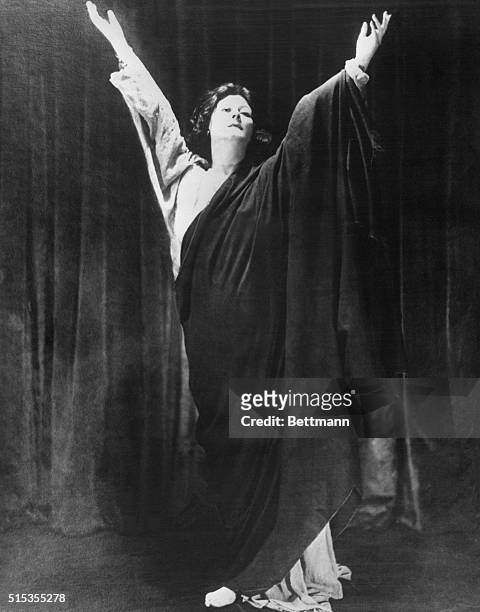 Portrait of dancer, Isadora Duncan, wearing a toga-like costume with her arms raised in the air. Undated photo circa 1910.
