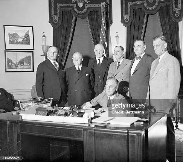 Washington, DC- President Roosevelt affixes his signature to the Industrial Control-Public Works bill, otherwise known as the National Recovery Act....