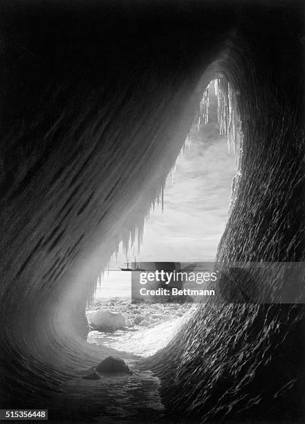 An arched iceberg reveals Robert Falcon Scott's ship, the Terra Nova, in the distance during his second Antarctic expedition.