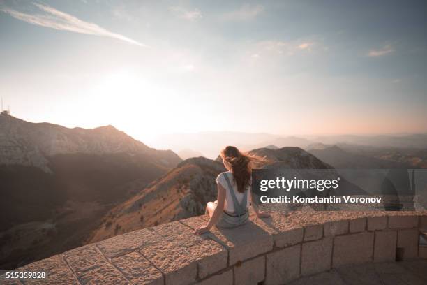 young woman looks across mountains and valley, sunrise - weggucken stock-fotos und bilder