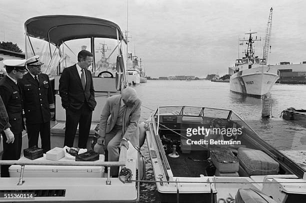 Miami, Florida: Standing on a boat confiscated from drug smugglers, Vice President George Bush looks over at bales of marijuana in another boat as...