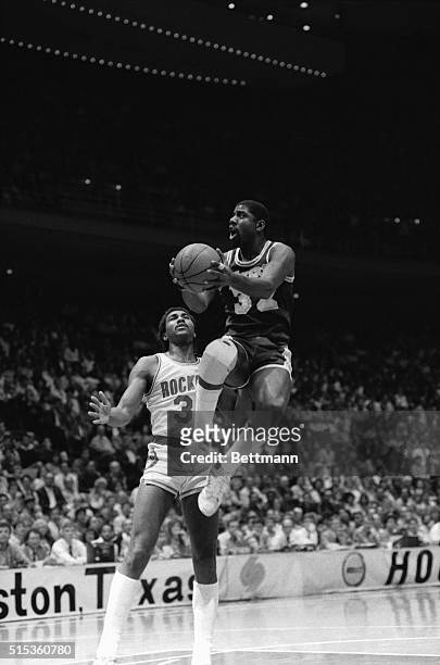 Los Angeles Lakers' Earvin "Magic" Johnson is airborne as he drives in for a lay up past Houston Rockets' Robert Reid in second quarter of the...