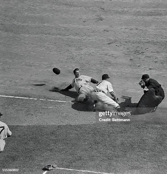 Cap flying in mid-air, Joe DiMaggio slides safely into third base on McQuinn's single to center in first inning of season's opener between New York...