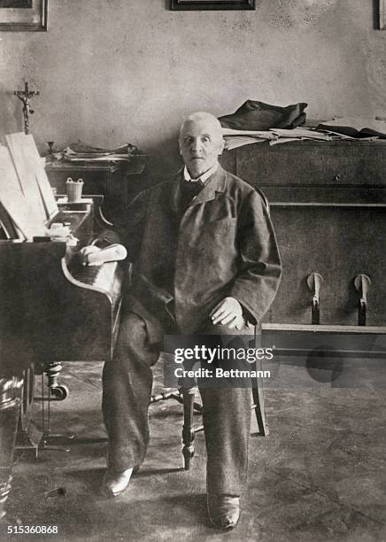 Bruckner in work room sitting at the side of his grand piano.