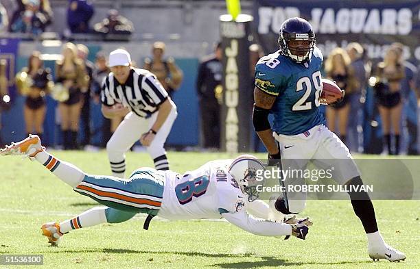 Fred Taylor of the Jacksonville Jaguars runs past a diving Calvin Jackson of the Miami Dolphins during the first half 15 January 2000, in their AFC...