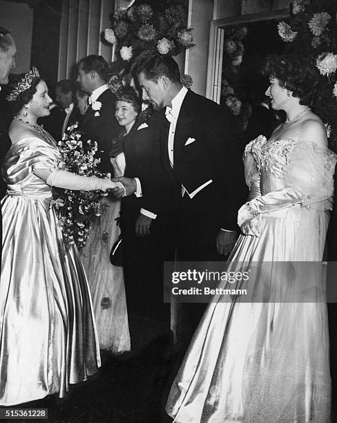 London: Royal Command Film Performance. Queen Elizabeth shaking hands with Errol Flynn, one of the stars of the command film, Forsyth Saga. Standing...