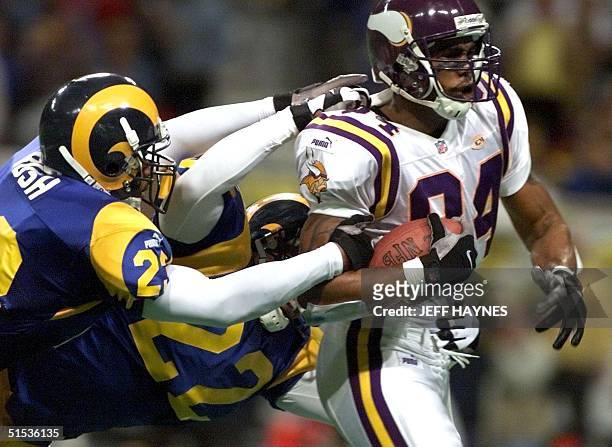 Wide receiver Randy Moss of the Minnesota Vikings is tackled down by Devin Bush and Billy Jenkins both of the St Louis Rams 16 January 2000 during...