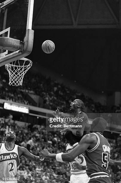 Bulls' Michael Jordan, top center, watches his shot go through the basket, while being held in the arms of Hawks' Cliff Levingston, partially hidden...